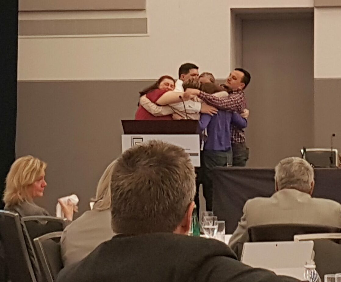 Numerous speakers at CALS in a group hug